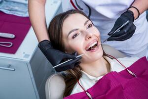 dentista examinando dientes de un joven mujer paciente en un dental clínica. odontología concepto. dentista y paciente en el dental oficina. foto