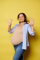 Smiling pregnant woman expecting a baby, showing nine fingers at camera. She's in last trimester of her happy pregnancy. photo