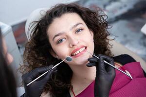 dentista examinando dientes de un joven mujer paciente en un dental clínica. odontología concepto. dentista y paciente en el dental oficina. foto