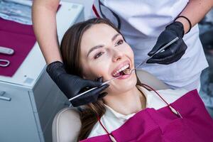 dentista examinando dientes de un joven mujer paciente en un dental clínica. odontología concepto. dentista y paciente en el dental oficina. foto