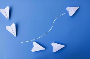 Top view of white paper airplanes with one flying at different direction. photo