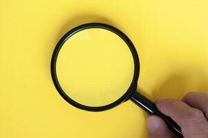 Top view of magnifying glass on yellow background with customizable space for text. photo