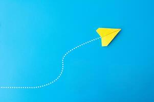 Top view of yellow paper airplane with line dots on blue background photo