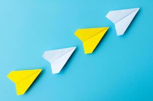 Top view of white and yellow paper airplanes origami flying on blue background photo