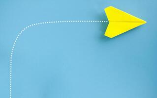 Top view of yellow paper airplane making turning on blue background. Business direction concept photo