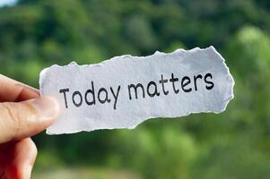 Today matters text on torn paper with hand holding on nature background photo