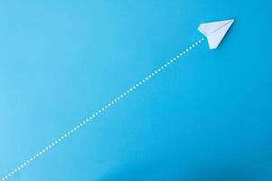 Top view of paper airplane with straight line dots on blue background photo