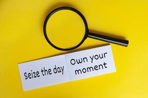 Seize the day text on white notepad with magnifying glasses on yellow cover background photo