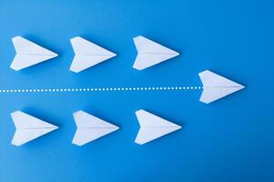 Top view of white paper airplanes origami with one flying ahead against all airplanes photo