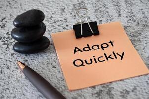 Adapt quickly text on notepad with zen stones and pen background. Adaptive management concept photo