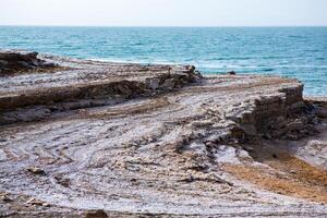 View of Dead Sea coastline at sunset time in Jordan. Salt crystals at sunset. Dead sea landscape with mineral structures. photo