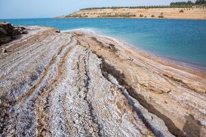 ver de muerto mar línea costera a puesta de sol hora en Jordán. sal cristales a puesta de sol. muerto mar paisaje con mineral estructuras foto
