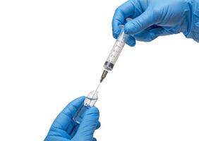 Medical gloved hand holding syringe with a bead of liquid emerging testing the function of the syringe photo