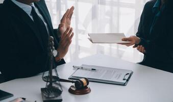 Justice and Law concept. Legal counsel presents to the client a signed contract with gavel and legal law or legal having team meeting at law firm in background photo