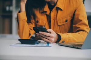 Asian businesswoman in formal suit in office happy and cheerful during using smartphone and working photo