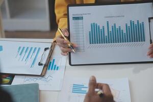 Financial analysts analyze business financial reports on a digital tablet planning investment project during a discussion at a meeting of corporate showing the results of their successful teamwork. photo