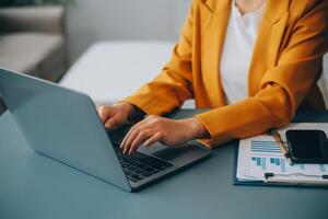 Happy millennial caucasian lady in suit typing on tablet at workplace with laptop in light office interior. Manager work, business with device, app, chat with client remotely photo