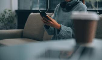 Happy pretty millennial Indian girl relaxing at home, resting in armchair, typing on smartphone, using online app, software, shopping on Internet, making video call. Mobile phone communication photo