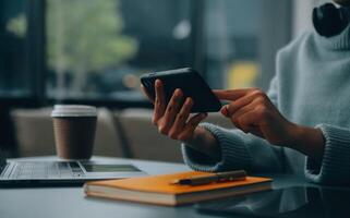 Happy pretty millennial Indian girl relaxing at home, resting in armchair, typing on smartphone, using online app, software, shopping on Internet, making video call. Mobile phone communication photo