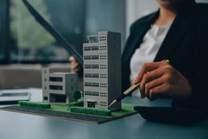 Close up realtor sit at table holds tiny house model, layout of cottage. Real estate purchase, new property, ownership, construction company make special offer to client, affordable dwelling concept photo