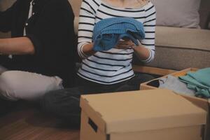 Two Asian blogger showing clothes in front of the camera to recording vlog video live streaming at her shop. Online Shopping Cart notion. on sofa at home photo