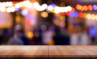 Empty wooden table top with lights bokeh on blur restaurant background. photo