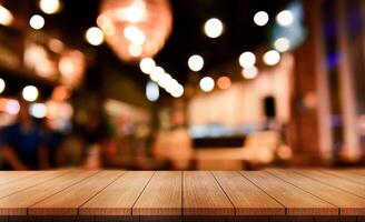 Empty wooden table top with lights bokeh on blur restaurant background. photo