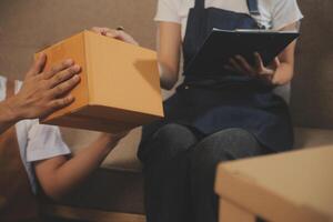 Two Asian blogger showing clothes in front of the camera to recording vlog video live streaming at her shop. Online Shopping Cart notion. on sofa at home photo