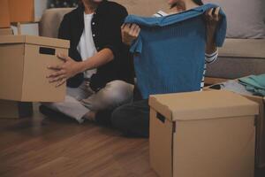 Two Asian blogger showing clothes in front of the camera to recording vlog video live streaming at her shop. Online Shopping Cart notion. on sofa at home photo