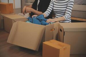 Two Asian blogger showing clothes in front of the camera to recording vlog video live streaming at her shop. Online Shopping Cart notion. on sofa at home photo