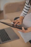 Young attractive asian woman resting using browsing tablet computer on sofa at home, happy girl sitting on couch relax reading digital gadget with excited, communication and lifestyle concept. photo