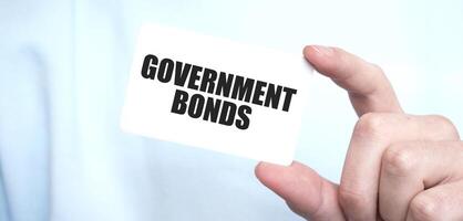 Man in blue sweatshirt holding a card with text GOVERNMENT BONDS, business concept photo