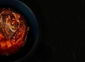 Top view of a Borsch soup plate, food frame, half plate close up isolated on black background. Ukrainian national food. photo