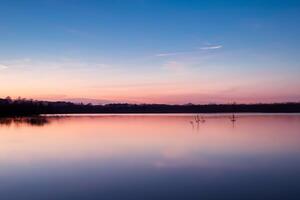 sereno aguas un feliz reflexión de un hermosa pastel lago y cielo, dónde tranquilidad Satisface de la naturaleza paleta, creando un armonioso oasis de suave matices y etéreo belleza foto