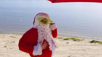 de kerstman claus in grappig bril Aan de oceaan strand video