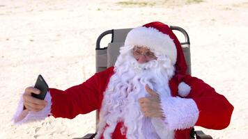 santa claus gör selfie liggande på en Sol vilstol på de strand video