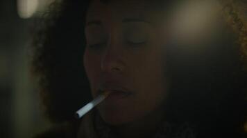 kvinna med lockigt hår belysning upp en cigarett utanför på natt video