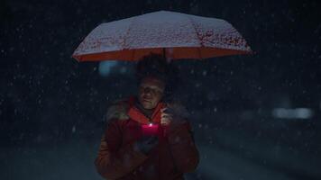 africano donna con afro acconciatura nel organge Abiti al di fuori nel forte nevicata video