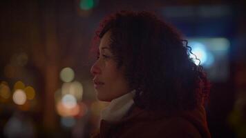 contento giovane donna con Riccio capelli danza al di fuori nel il città notte luci video