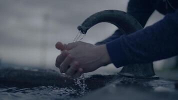 persona lavaggio mani al di fuori a acqua Fontana nel lento movimento video