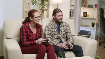 Mann und Ehefrau Sitzung auf Sofa spielen Video Spiele mit kabellos Regler.