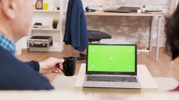 Back view of elderly age couple sitting on sofa while waving at laptop with green screen. video