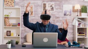 anziano uomo utilizzando virtuale la realtà occhiali nel vivente camera. donna Guardando tv mentre seduta su il divano nel il sfondo. video