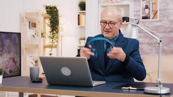 senior oud Mens luisteren muziek- Aan hoofdtelefoons terwijl werken Aan laptop in leven kamer. vrouw gebruik makend van tablet in de achtergrond. video