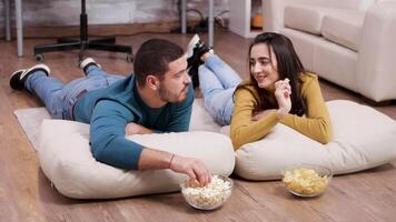 jovem mulher sorridente às dele namorado enquanto assistindo televisão sentado em a chão. video