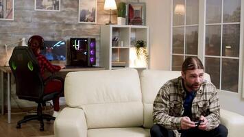 Upset man throwing wireless controller on the couch after losing after playing video games. Girlfriend in the background.