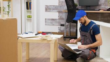 Furniture assembly worker uses laptop to consult instructions. Handyman doing a good job. video