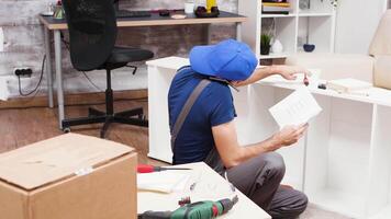 Male worker talking on the phone listening instructions fir furniture assembly in new apartment. video