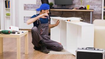 Zoom in shot of man in overalls assembles a shelf and reading instruction. video