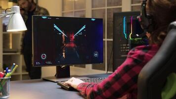 Woman with headphones sitting on gaming chair playing video games on computer. Game over for female gamer. Man talking on phone in the background.